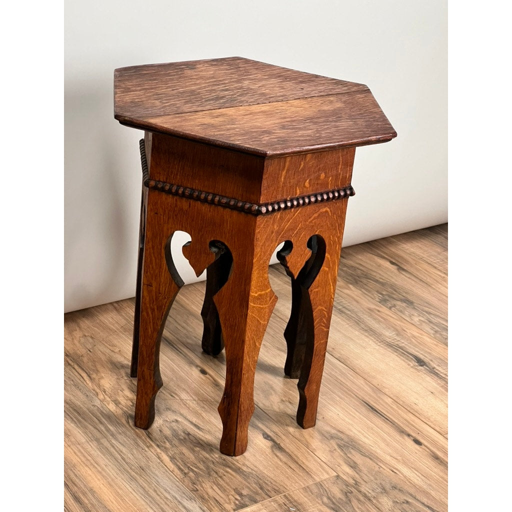 The Antique Arts & Crafts Small Oak Occasional Table c. 1910 features a hexagonal top, beaded edge, and cut-out patterned legs, epitomizing classic Arts and Crafts style when placed on a wood floor against a light wall.
