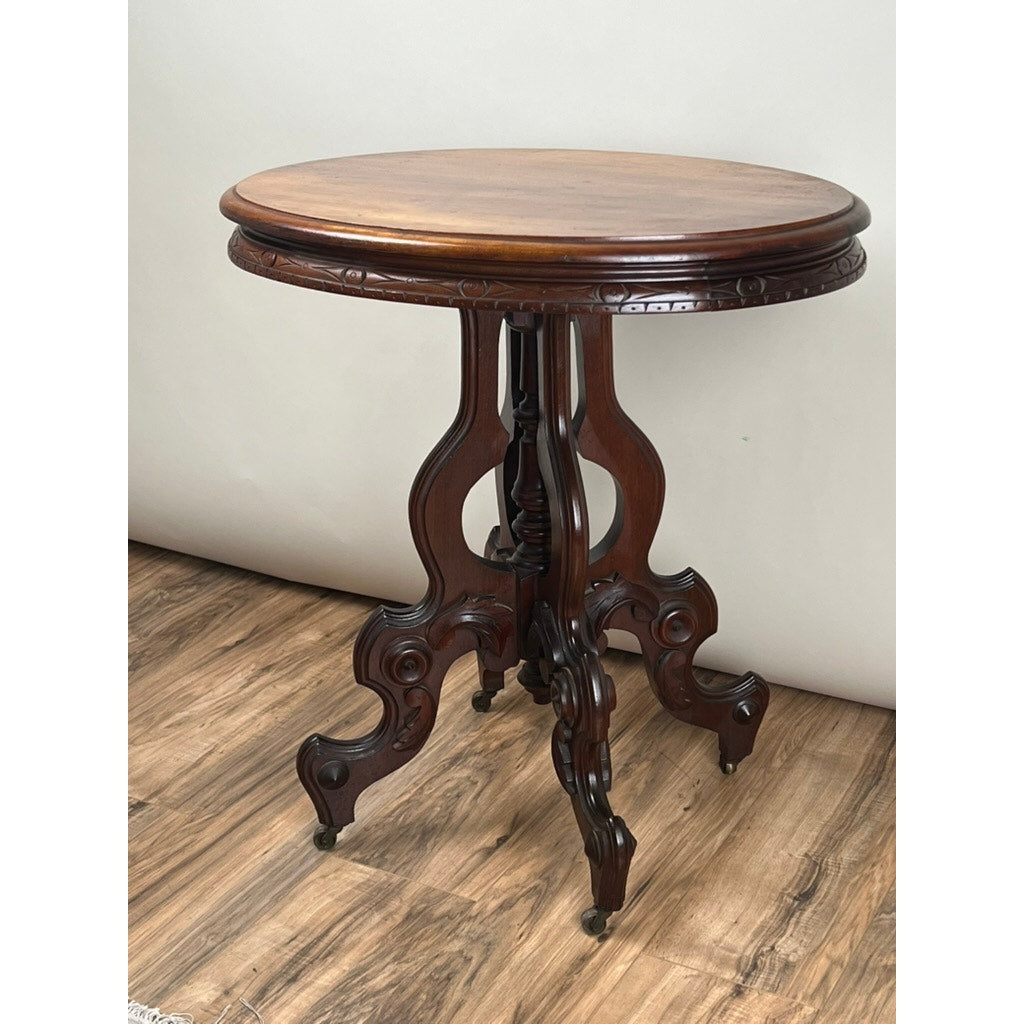 The Antique Victorian Walnut Lamp Stand, dating from the late 19th century, features ornate carved legs and a polished surface. This accent table stands on a wood floor against a plain light background. Brand: Unknown.