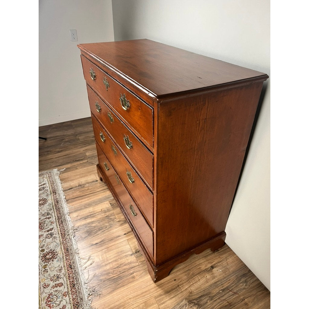 An Antique Chippendale Pine Graduated Four Drawer Chest, attributed to a late 18th-century Northampton MA maker, stands on a hardwood floor by a rug and white wall. Its polished finish and traditional design echo classic Chippendale style.