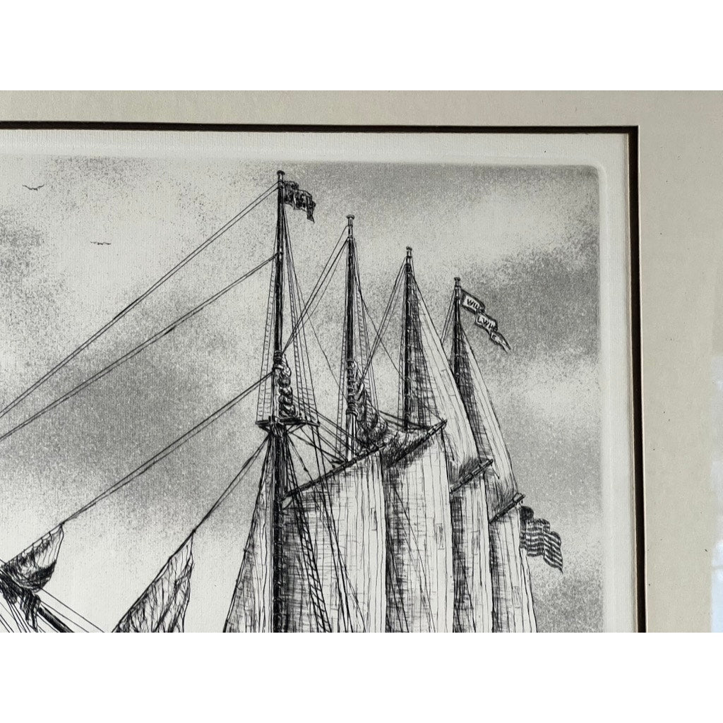 Framed Etching “The Schooner” by Alan Jay Gaines features a black and white sketch of tall masts, rigging lines, and flags—including an American flag—set against a cloudy sky in this striking piece of maritime art.