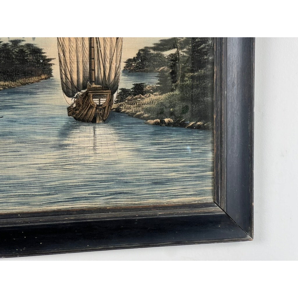 Close-up of a framed Japanese Meiji Period embroidered painting, attributed to Nishimura Sozaemon of Kyoto, depicting an intricately detailed sailboat on a river amid trees and greenery; only the boat’s lower half is shown in silk.