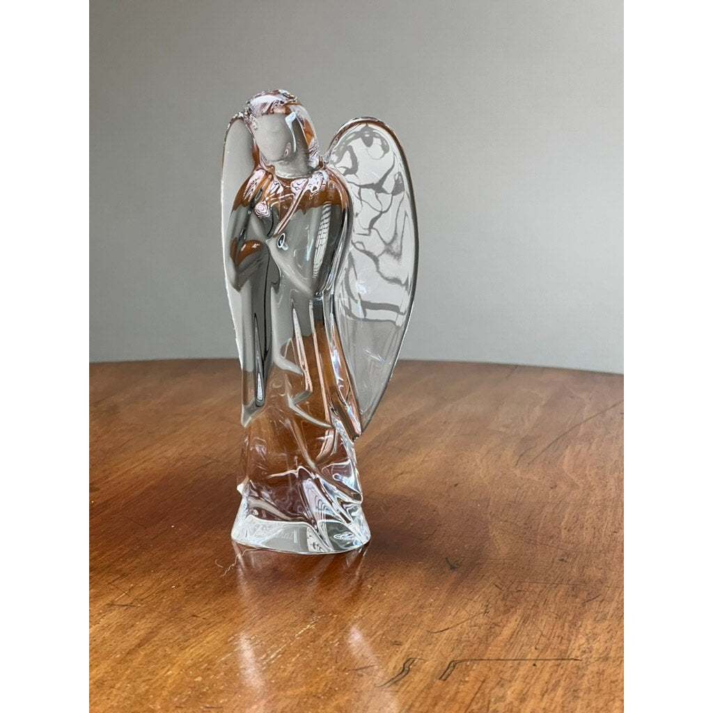 The Vintage Baccarat Crystal Angel by Baccarat features clear wings and a brown-tinted body, displayed on a wooden surface against a plain gray background.