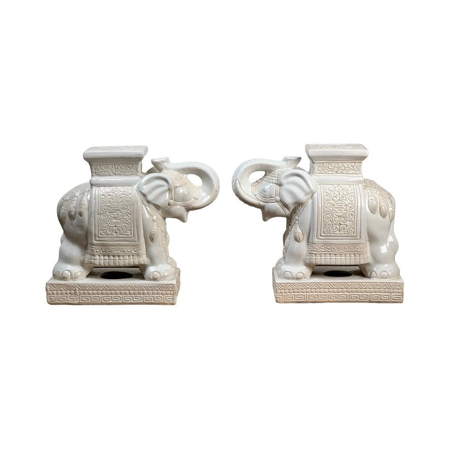 This Vintage Pair of White on White Glazed Hollywood Regency Style Elephant Garden Seats features ornate saddle-like decorations, flat tops, and rectangular bases with embossed patterns—an elegant accent for any space.