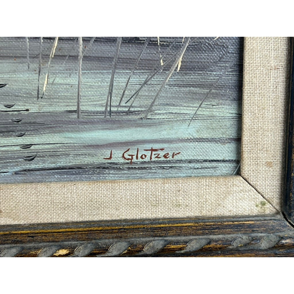 Close-up of the corner of “Mallards Over Marsh” oil on canvas by Joseph Glotzer, featuring a beige textured frame and “J Glotzer” signature in red on a muted blue-green and gray landscape with visible brushstrokes.