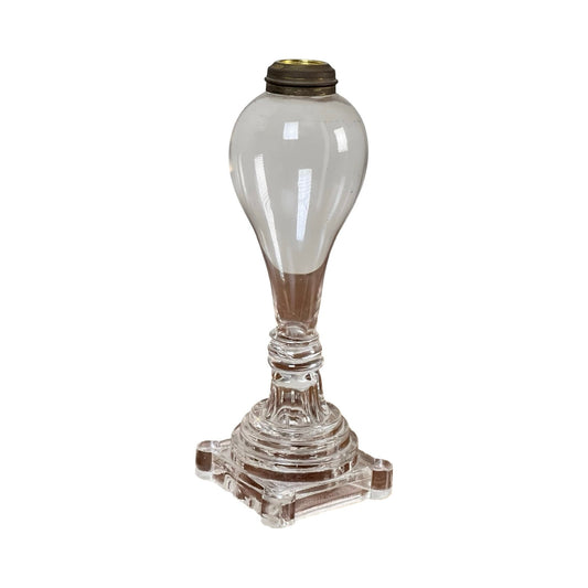 Attributed Boston & Sandwich Pressed Glass Boudoir Fluid Lamp, Circa 1850. This clear pressed glass oil lamp base showcases an ornate, tiered design, with a round bulbous upper section and a square pedestal bottom. Reminiscent of the early American mid-19th century boudoir fluid lamps, it features a brass fitting at the top for attaching a burner or chimney. Brand: None/Unknown.
