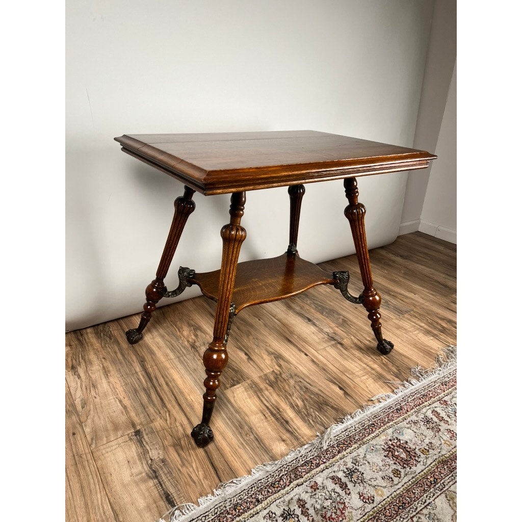 An Antique Victorian Oak Lamp Stand with Bronze Lions Head Mountings, c. Late 19th Century, stands on a wood floor beside a patterned rug and against a plain light-colored wall.