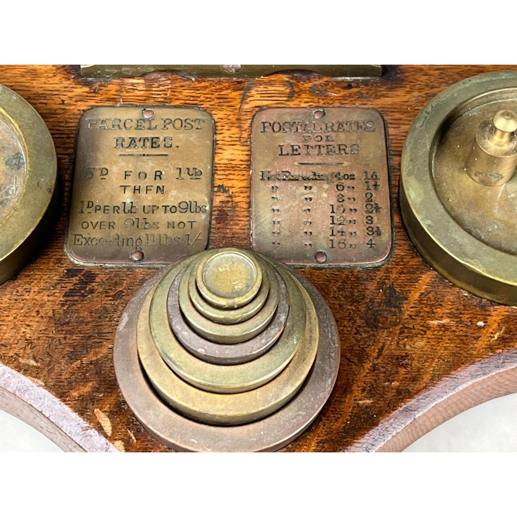 Antique 19th Century English Postal Scale featuring brass construction, round nested weights, two metal rate plaques for parcels and letters, all mounted on a wooden base. A classic Victorian collectible scientific instrument. Brand: Unknown.