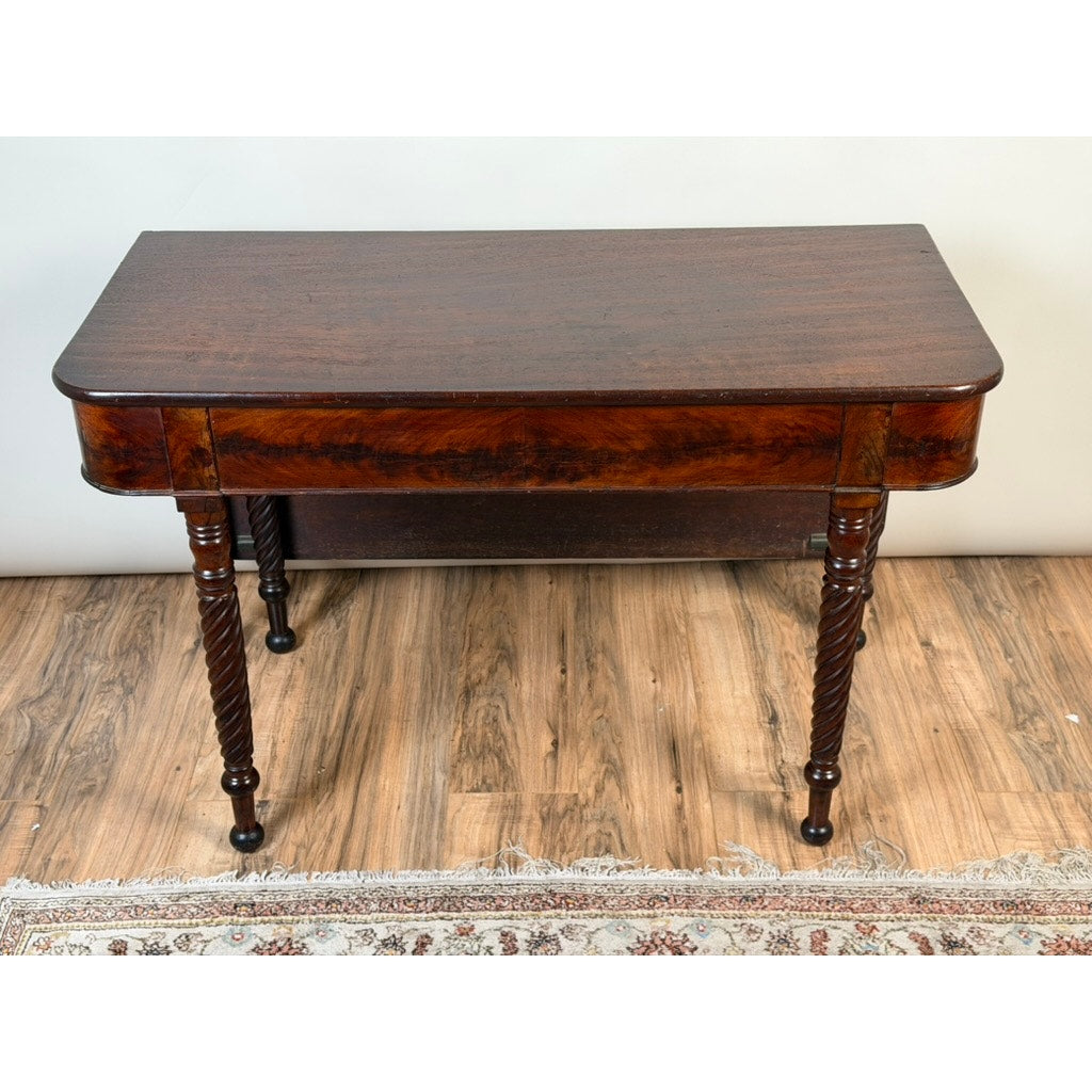 An American Classical Mahogany Single Drop-Leaf Table with Spiral-Twist Legs, c. 1830–1845 by Pearl City Antiques sits on a wood floor near a patterned rug. This vintage piece features a dark, polished mahogany finish and a rectangular top with slightly rounded edges.