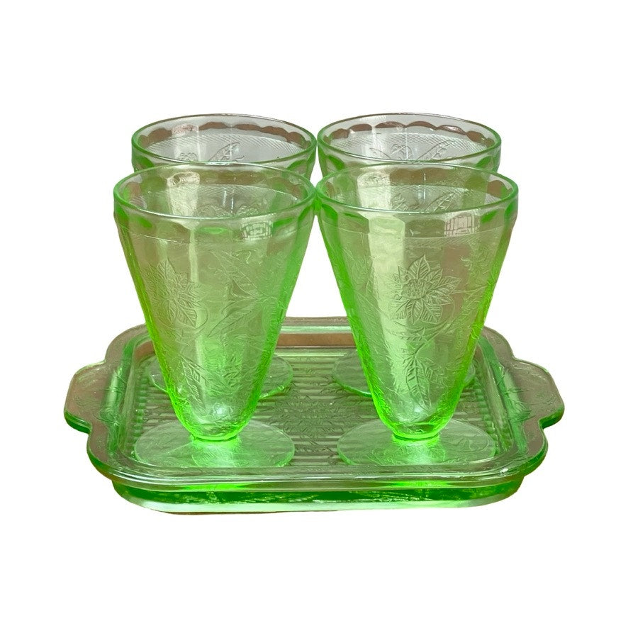 Antique Jeannette Glass Co. Green Uranium Floral Poinsettia 5-piece beverage set from the 1930s includes four tumblers with floral patterns and a matching handled tray, all displayed against a white background.