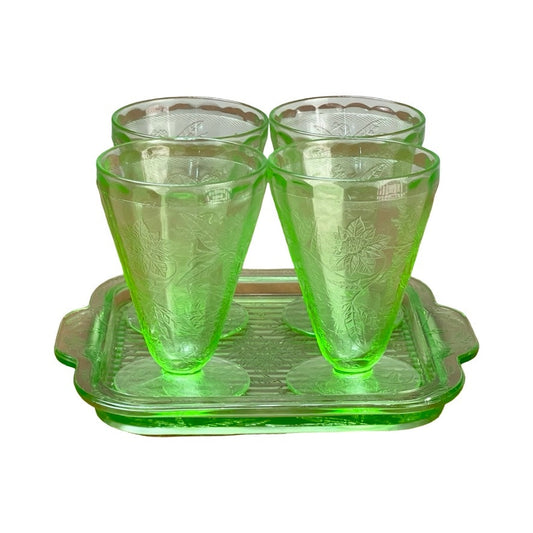 Antique Jeannette Glass Co. Green Uranium Floral Poinsettia 5-piece beverage set from the 1930s includes four tumblers with floral patterns and a matching handled tray, all displayed against a white background.