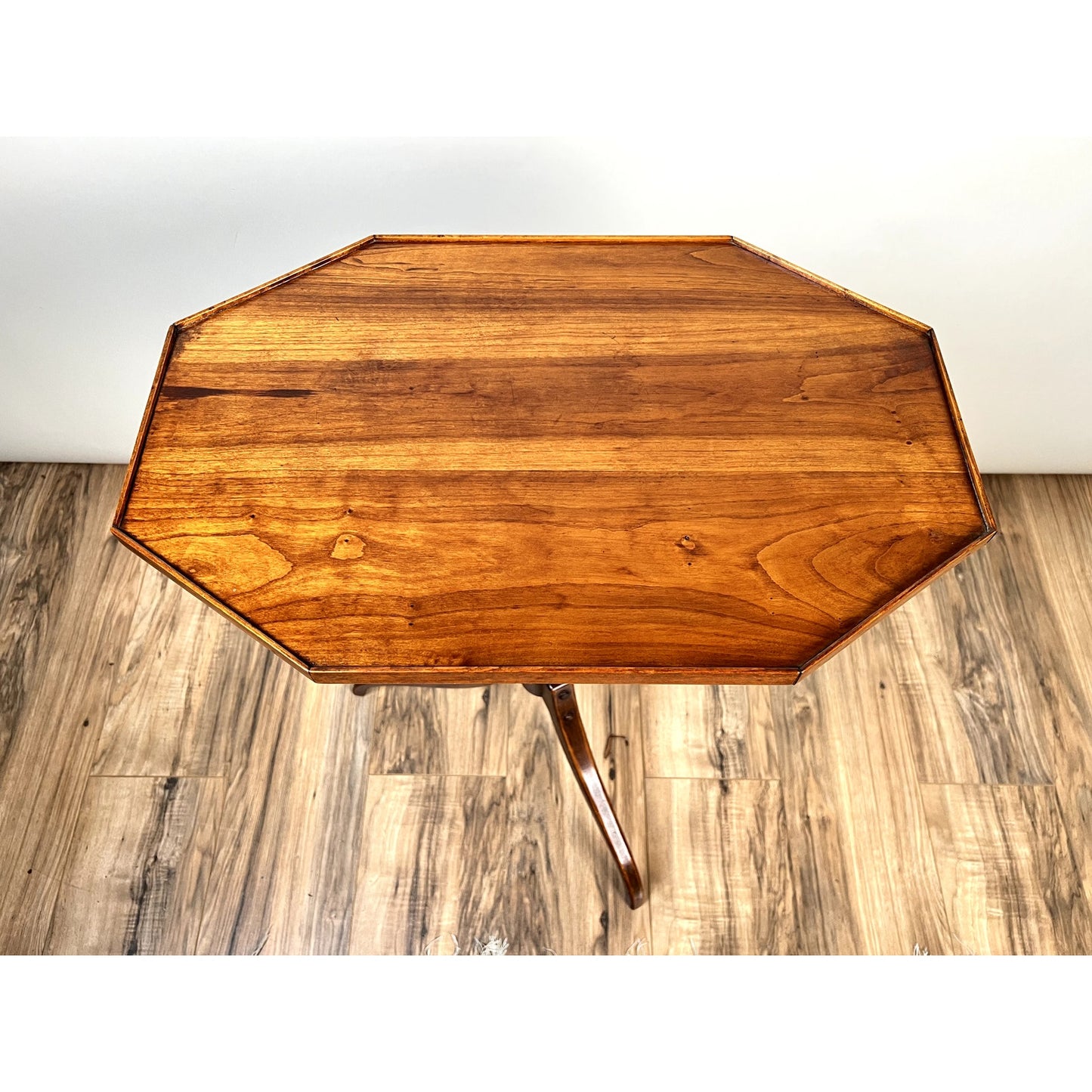 The Vintage Federal Style Cherry Octagonal Tilt Top Candlestand by Stickley stands on a light wood floor against a white wall, showcasing its polished surface and elegant tripod base.