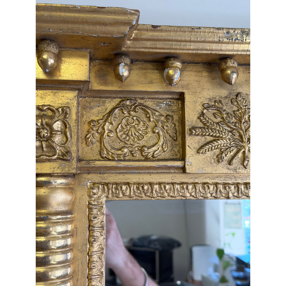 Detail of an American Federal Giltwood Pier Mirror, circa 1815–1830, featuring a gilded wooden frame with carved floral motifs, acanthus leaves, and a row of acorn-shaped ornaments along the cornice.