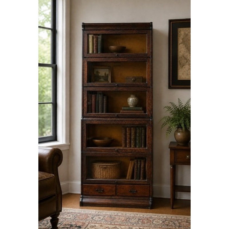 The Antique Hale System Quarter-Sawn Oak Five-Stack Barrister Bookcase by Camden Cabinet Company, c. 1910, features glass-front shelves ideal for displaying books and decorative items, with two drawers at the bottom. It is positioned near a window, next to a leather chair and a small table topped with a fern plant, beneath a framed map on the wall.