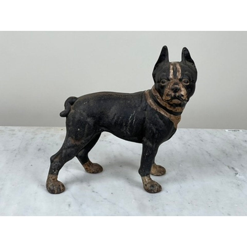 The Hubley Antique Cast Iron Boston Terrier Doorstop, styled as a black and brown dog with cropped ears and a short tail, stands on a white marble surface against a plain light background.