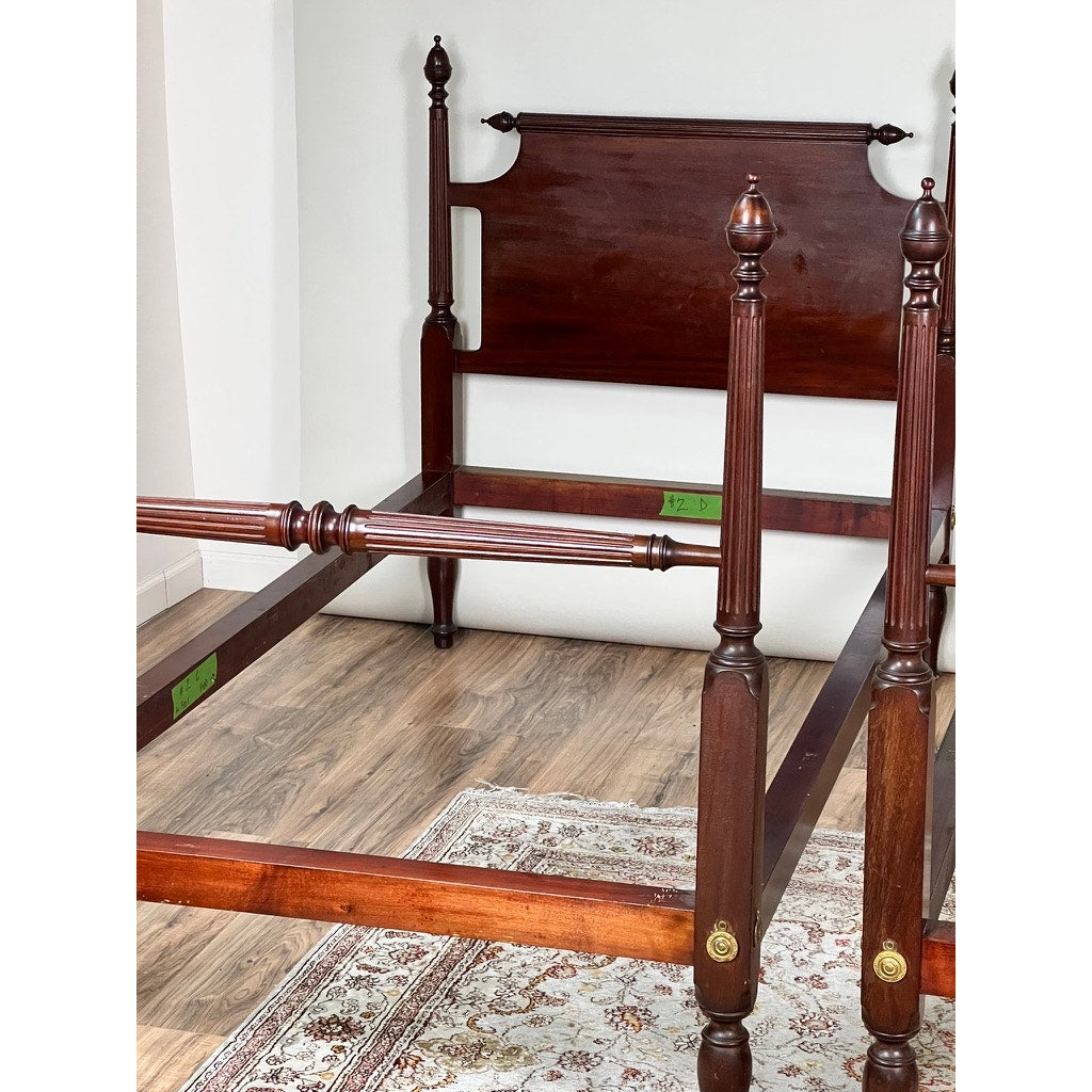 A Vintage Pair Centennial Solid Mahogany Twin Four Poster Bed c. 1940 stands on a floral rug atop a wood floor in a bright room, displaying only its tall wooden frame with the mattress missing. Brand: Unknown.
