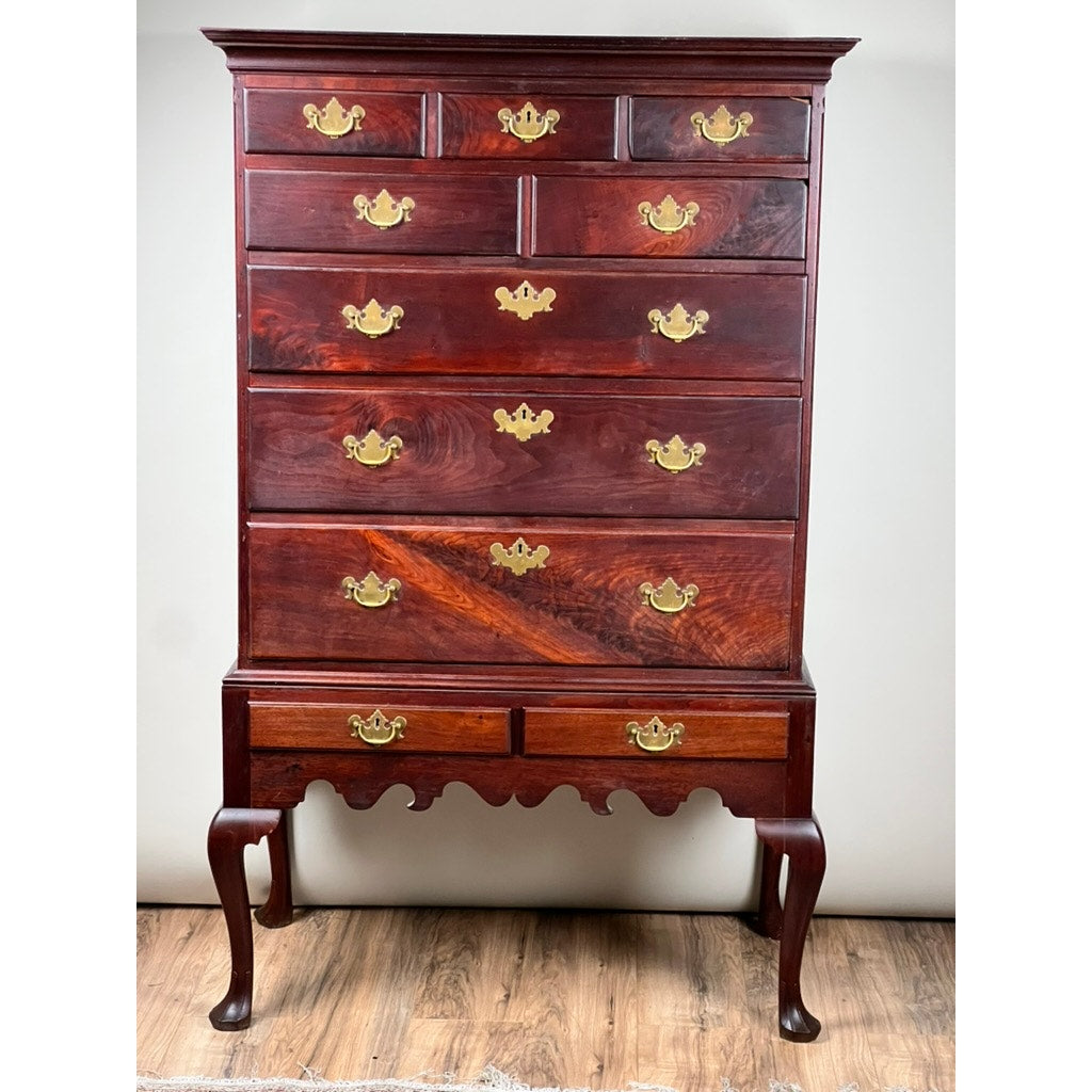 An Antique Queen Anne Walnut Chest on Frame with Drake Feet, probably Irish from the late 18th century, stands elegantly on a wooden floor against a plain wall, showcasing its rich walnut finish and classic drake feet.