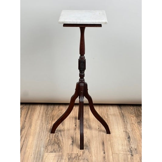 A late 19th-century Antique Victorian Marble Top Plant Stand by Pearl City Antiques, featuring a square white marble top and three elegantly curved legs, is positioned on a wooden floor against a plain light-colored wall.