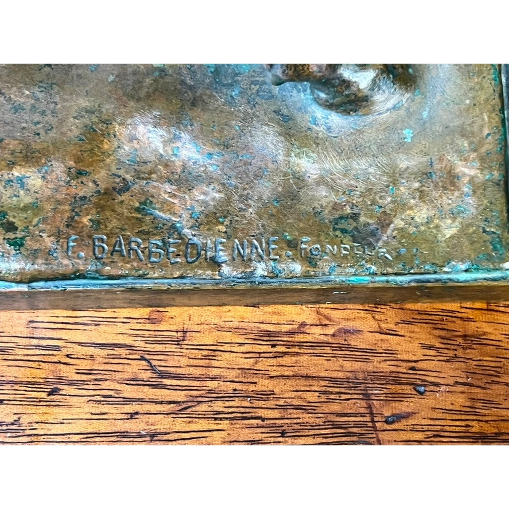 Close-up of the base of Jean-Baptiste Clesinger’s "Taureau Romain" bronze sculpture, Barbedienne Foundry, Rome 1858, showing “C. BARBEDIENNE. FONDEUR” engraved above textured wood and weathered bronze with green patina.
