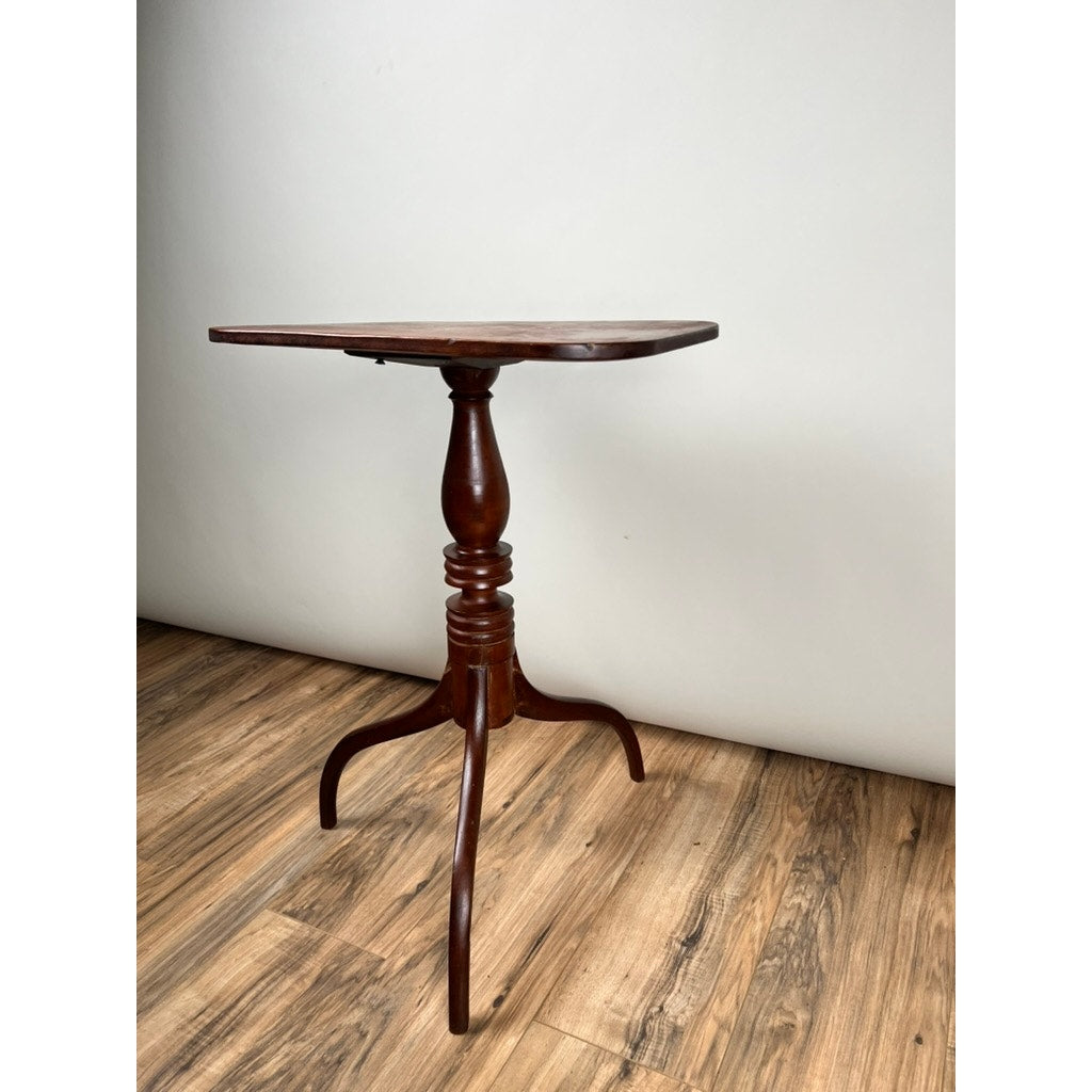 An Antique Federal Period Cherry Hepplewhite Candle Stand, c. mid-19th century, with a square top and three curved legs, stands on a wood-patterned floor against a plain white wall. Brand: Unknown.