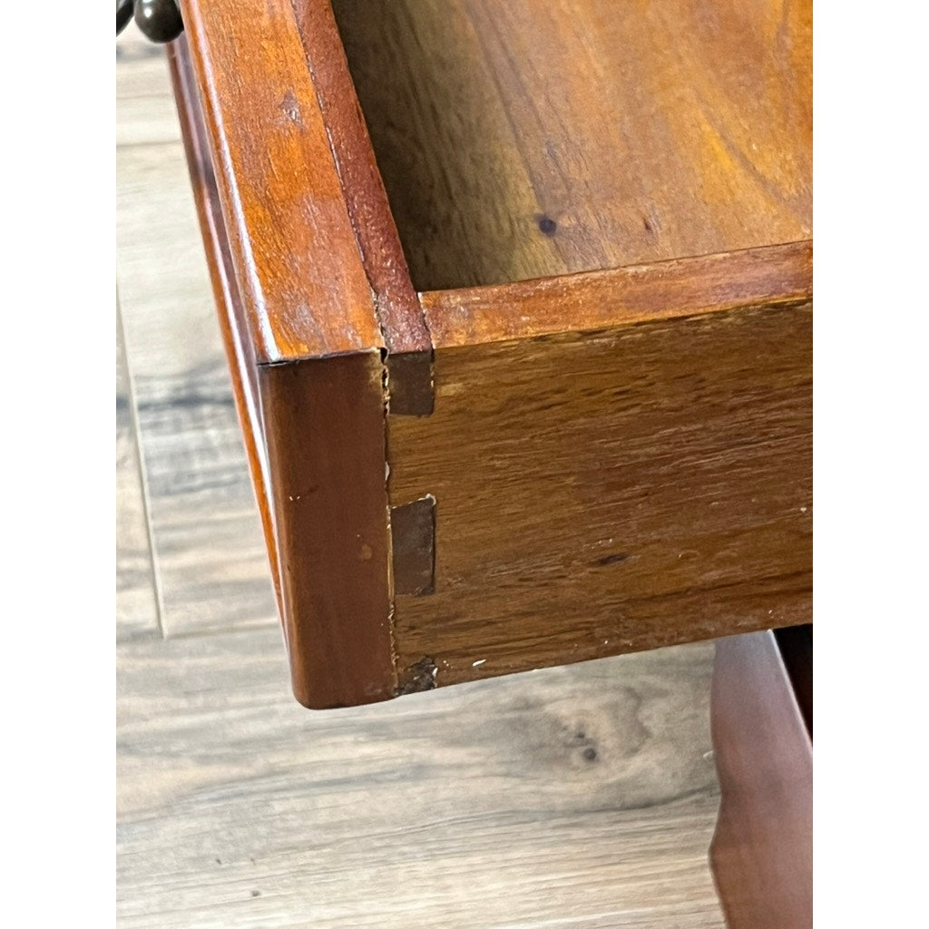 Close-up of a wooden drawer’s side with dovetail joints and polished brown finish, partially open above a wood-patterned floor; detail from a Vintage Victorian Style Glass Door Mahogany Bookcase (brand unknown).