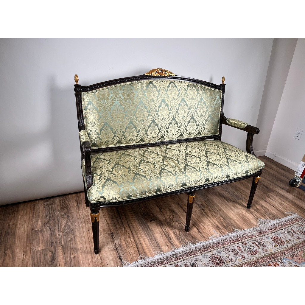 A Vintage Louis XVI Style Settee in green damask upholstery sits on a wooden floor beside a patterned rug in a room with plain light-colored walls. Brand is unknown.