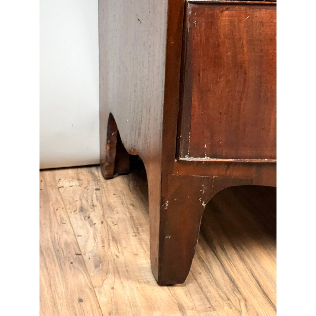 Close-up of the bottom corner of an Antique George III Mahogany Bowfront Chest on French Feet (late 18th century), with visible wood grain, scratches, and scuffs near the legs highlighting its authentic Georgian period charm.