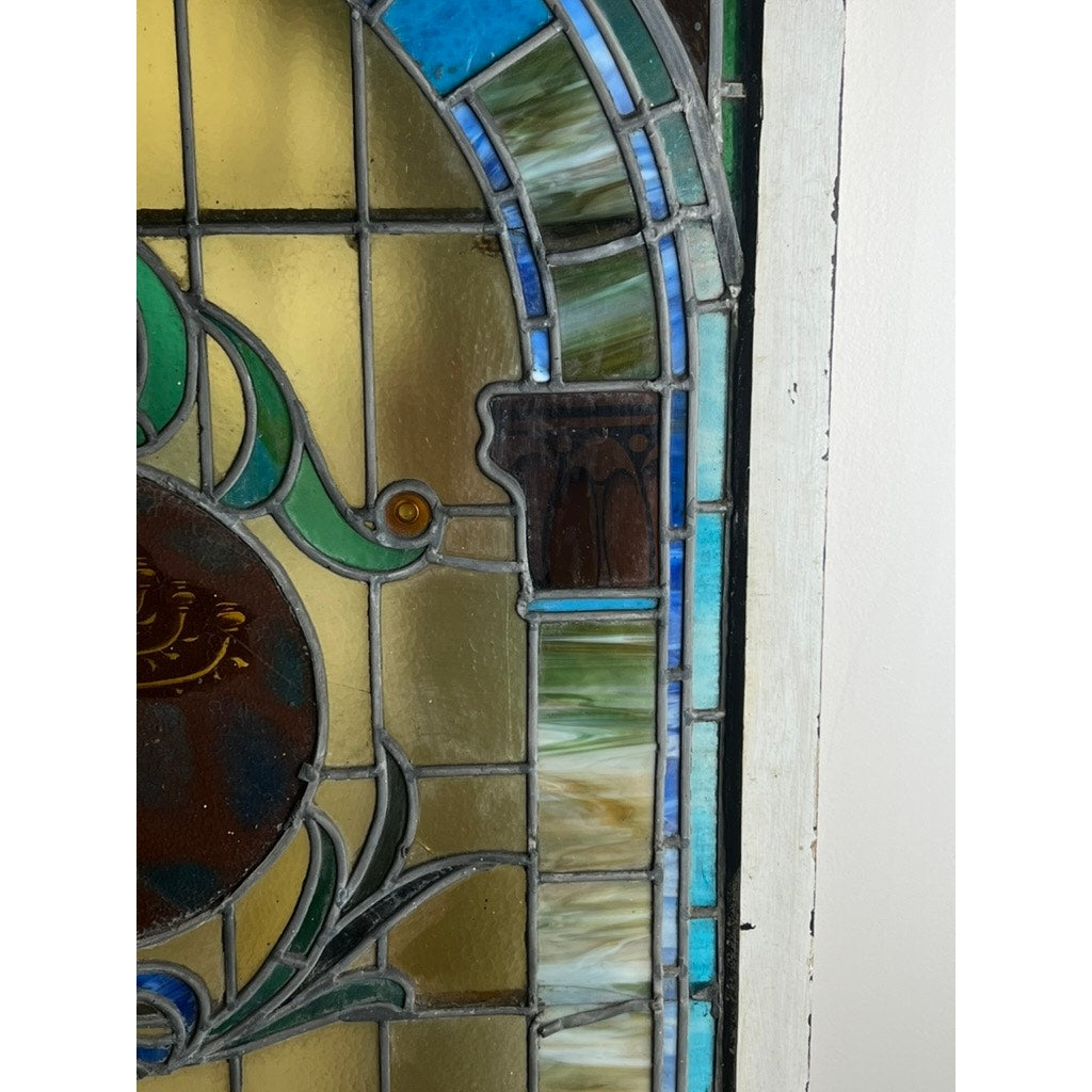 Antique stained glass with arched design and colorful geometric borders