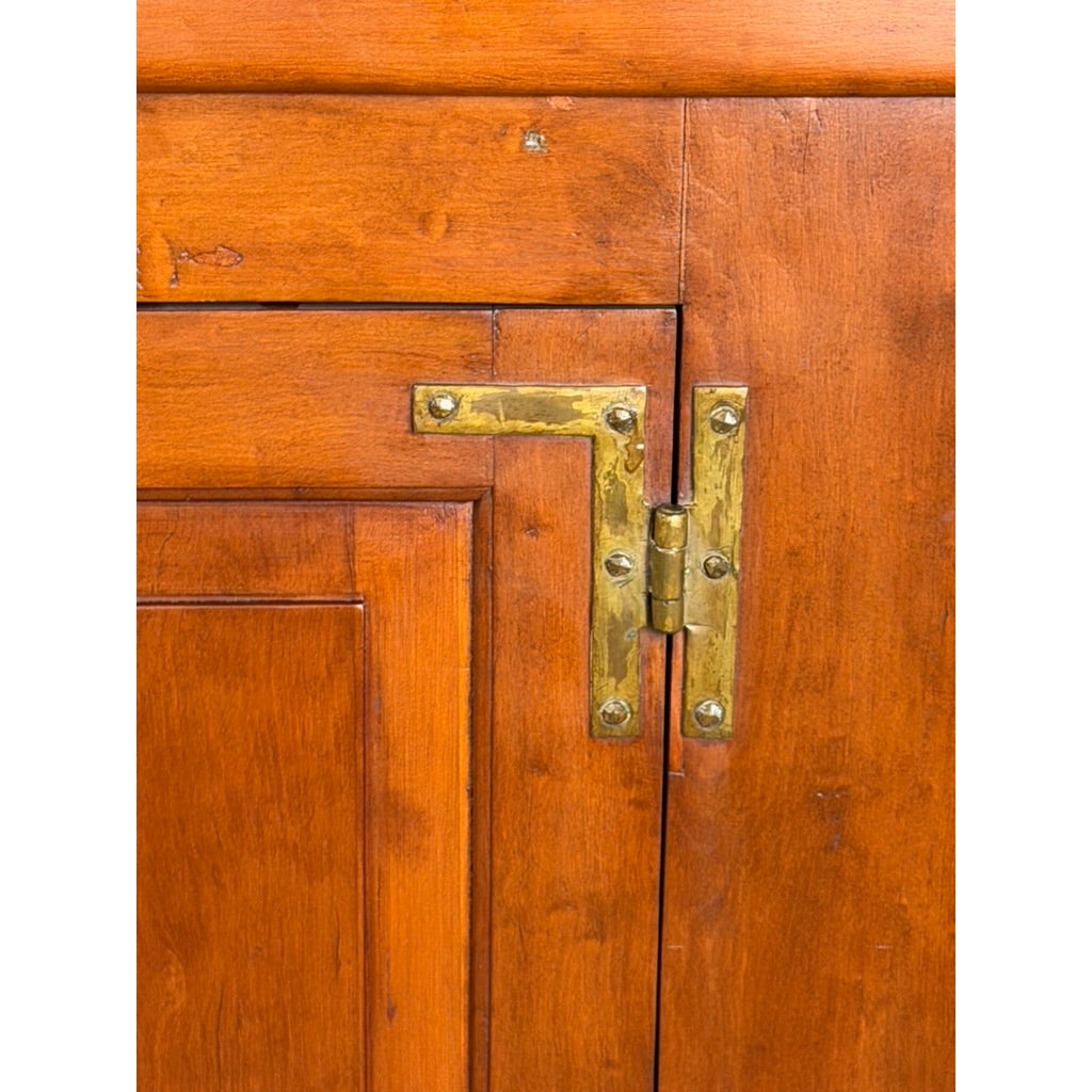 Close-up of a brass L-shaped hinge on a Pennsylvania or Mid-Atlantic Cherry Open Pewter Cupboard door.