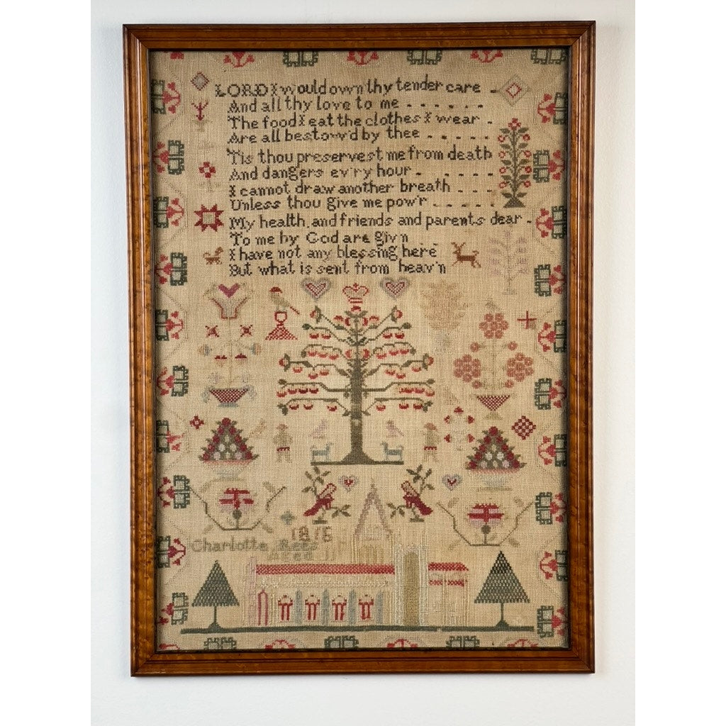 An exceptional English Regency schoolgirl needlework sampler by Charlotte Rees, age 11, dated 1816. This exquisite antique piece features a central tree, decorative motifs, and a stitched prayer about gratitude and blessings. Framed by geometric patterns and small houses, the sampler is delicately signed “Charlotte” with the year “1816” at the bottom, beautifully showcasing Charlotte Rees’s artistry at just eleven years old.