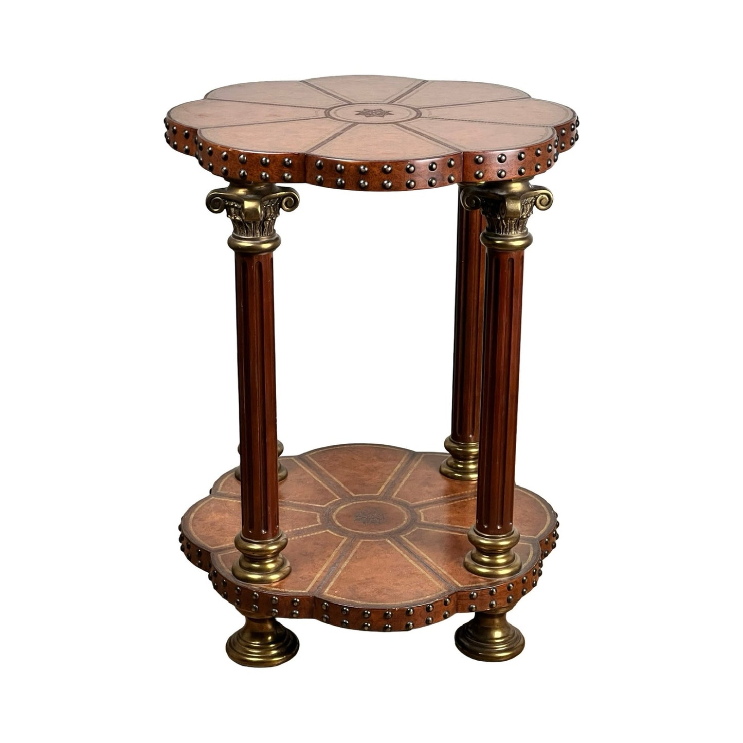 The Vintage Maitland-Smith Leather-Clad Occasional Table by Maitland Smith features two tiers, fluted legs with classical columns, ornate brass nailhead trim, carved floral motifs, and decorative studs.