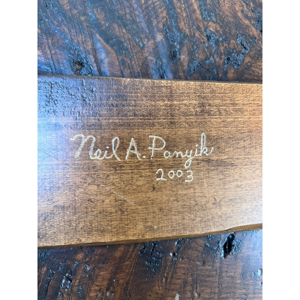 A rustic Vintage Hand Made Oak Wabi Sabi Bench, signed "Neil A. Panyik 2003," features artisanal charm with light script on the dark wood grain; brand is unknown.