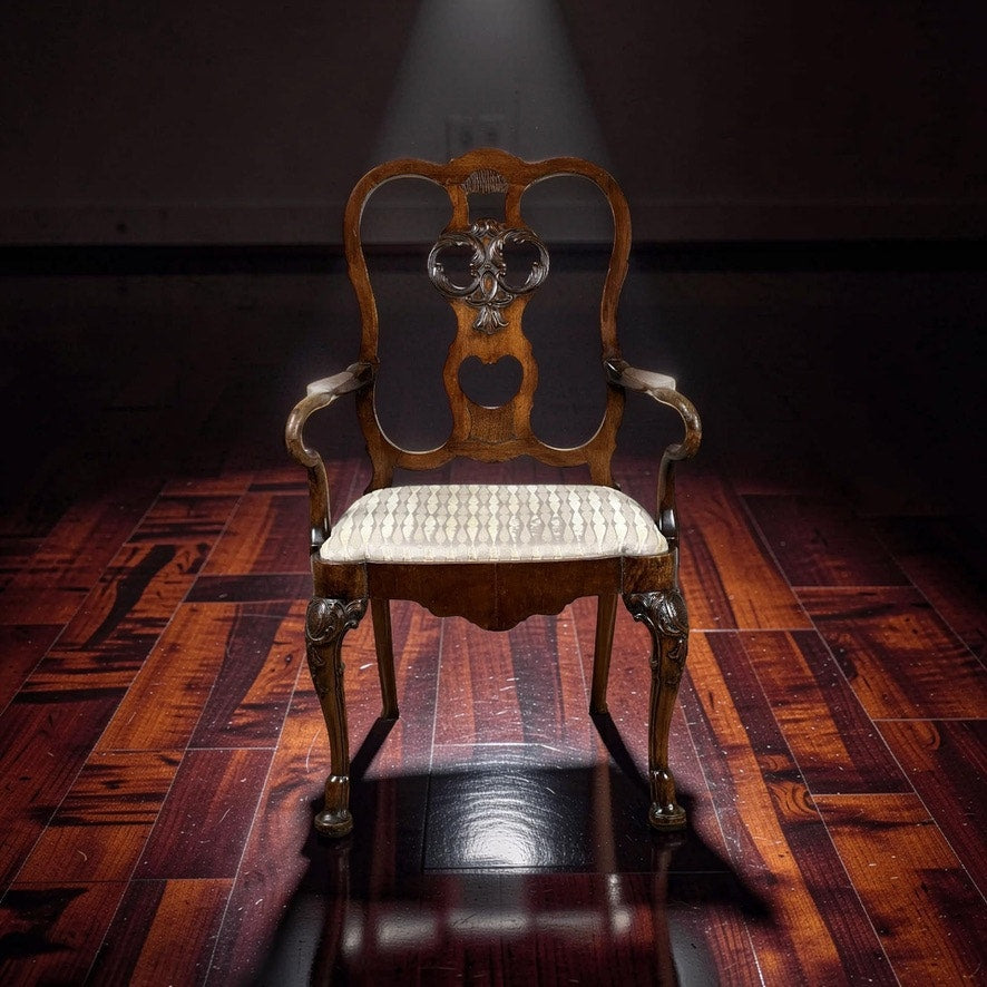 An Antique George III Mahogany Open Arm Chair (late 18th century) is highlighted on a polished, dark wooden floor in a dimly lit room, showcasing its ornate backrest and patterned seat cushion. Brand unknown.