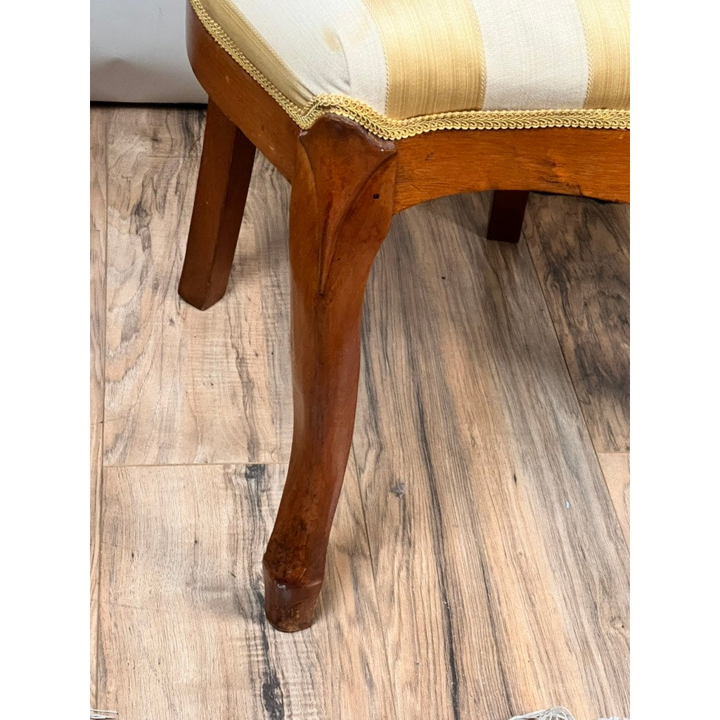 Close-up of a Pair Antique Victorian Balloon Back Chairs c. Late 19th Century, featuring carved light wood legs and cream-yellow striped upholstery, reminiscent of elegant antique 19th-century collections. Shown on a wood-patterned floor. Brand: Unknown.