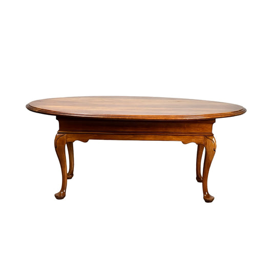 Vintage solid cherry Queen Anne style coffee table, attributed to Pennsylvania House, features a polished oval surface and curved legs, displayed against a white background.