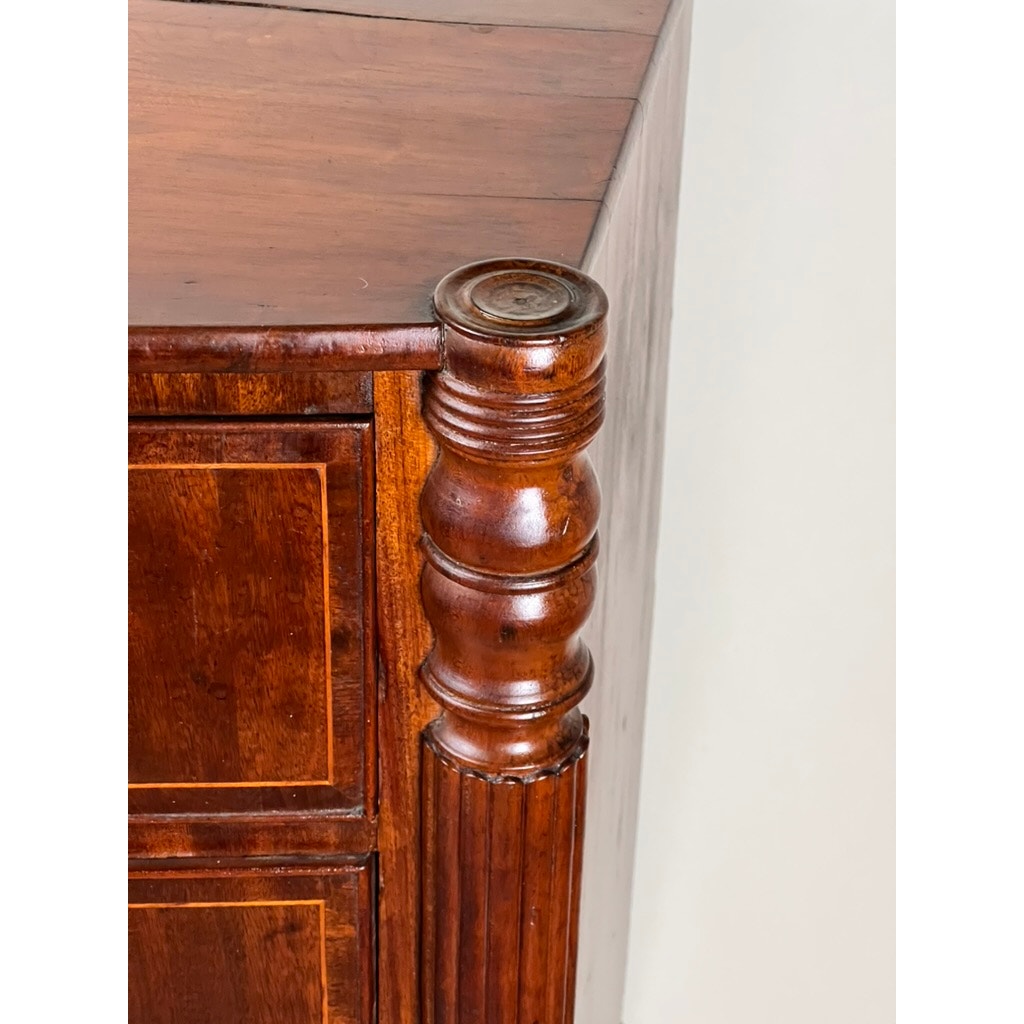 Close-up of the corner of an Antique Sheraton Mahogany Bowfront Chest (Early 19th Century) with polished, turned column detail and paneled drawer fronts, highlighting fine craftsmanship and rich mahogany grain.