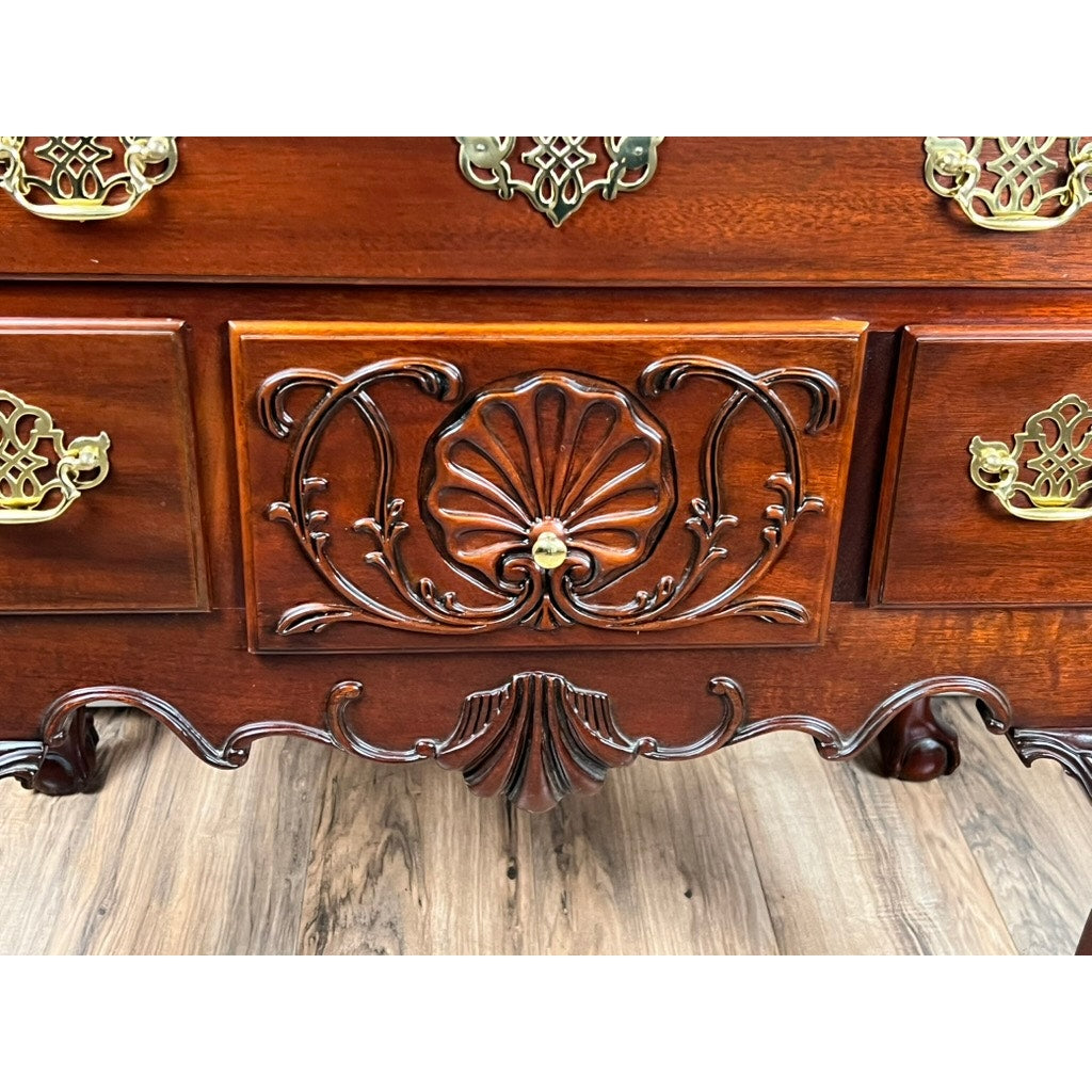 A close-up of the Vintage Solid Mahogany Chippendale Style Lowboy by Councill Craftsmen, showing its ornate shell-carved details and brass handles, set on a wood floor.