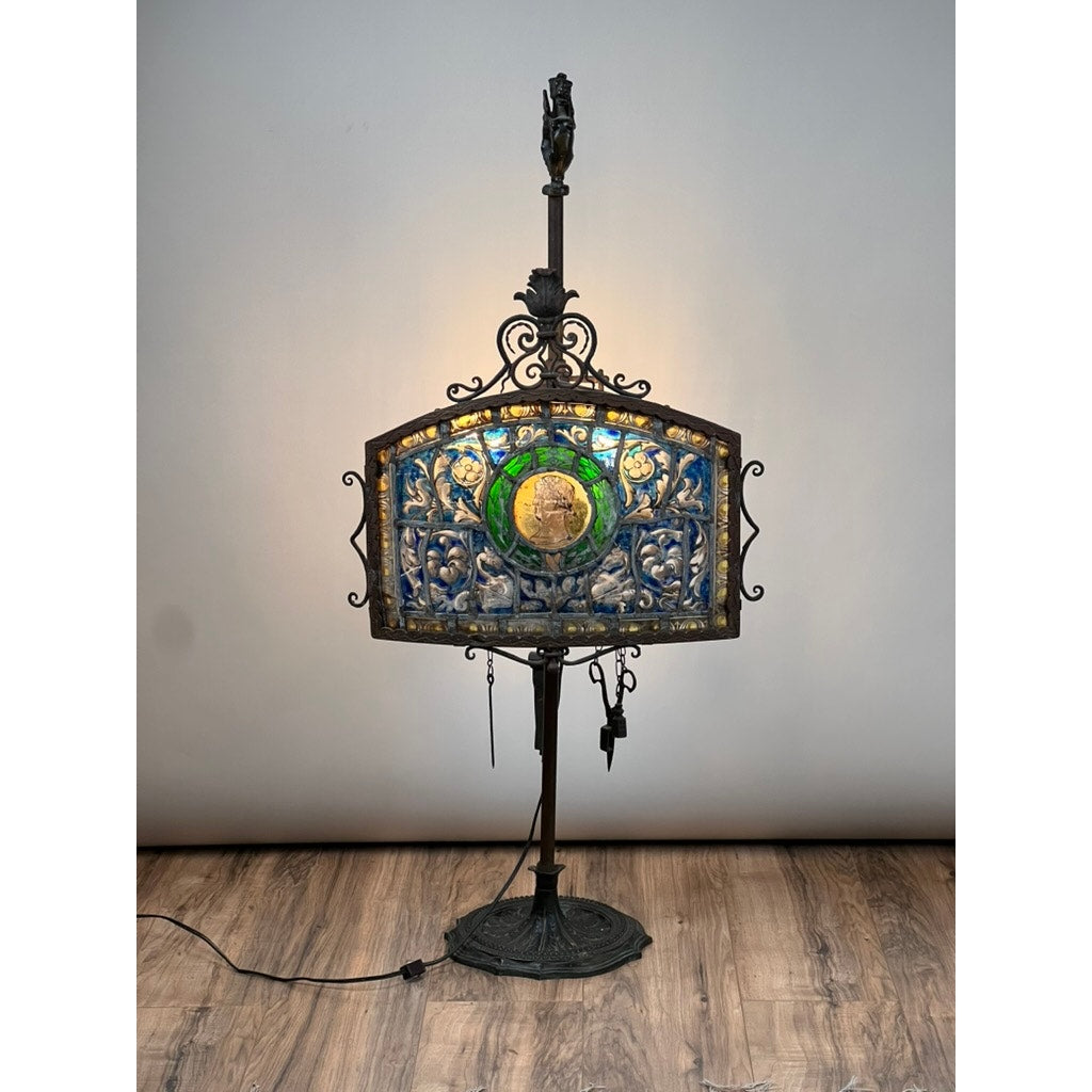An Antique Five Burner Lucerne Whale Oil Lamp with a Napoleon I Fireplace Screen Shade stands on a wooden floor against a plain gray wall, evoking vintage charm despite an unknown brand.
