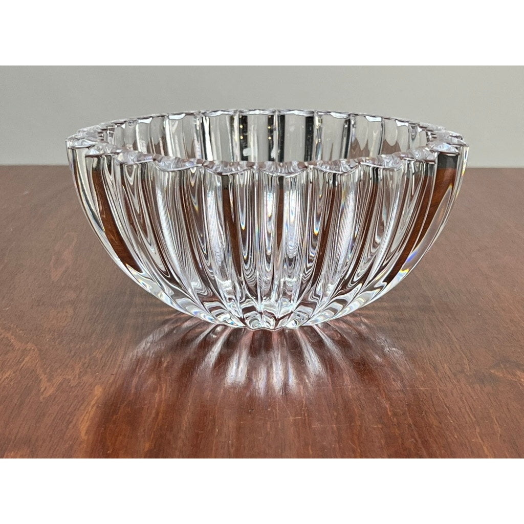 The Vintage Tiffany & Co. Crystal Bowl in a ribbed petal design by Tiffany & Co. rests on a wooden surface against a plain background, creating an elegant crystal centerpiece.