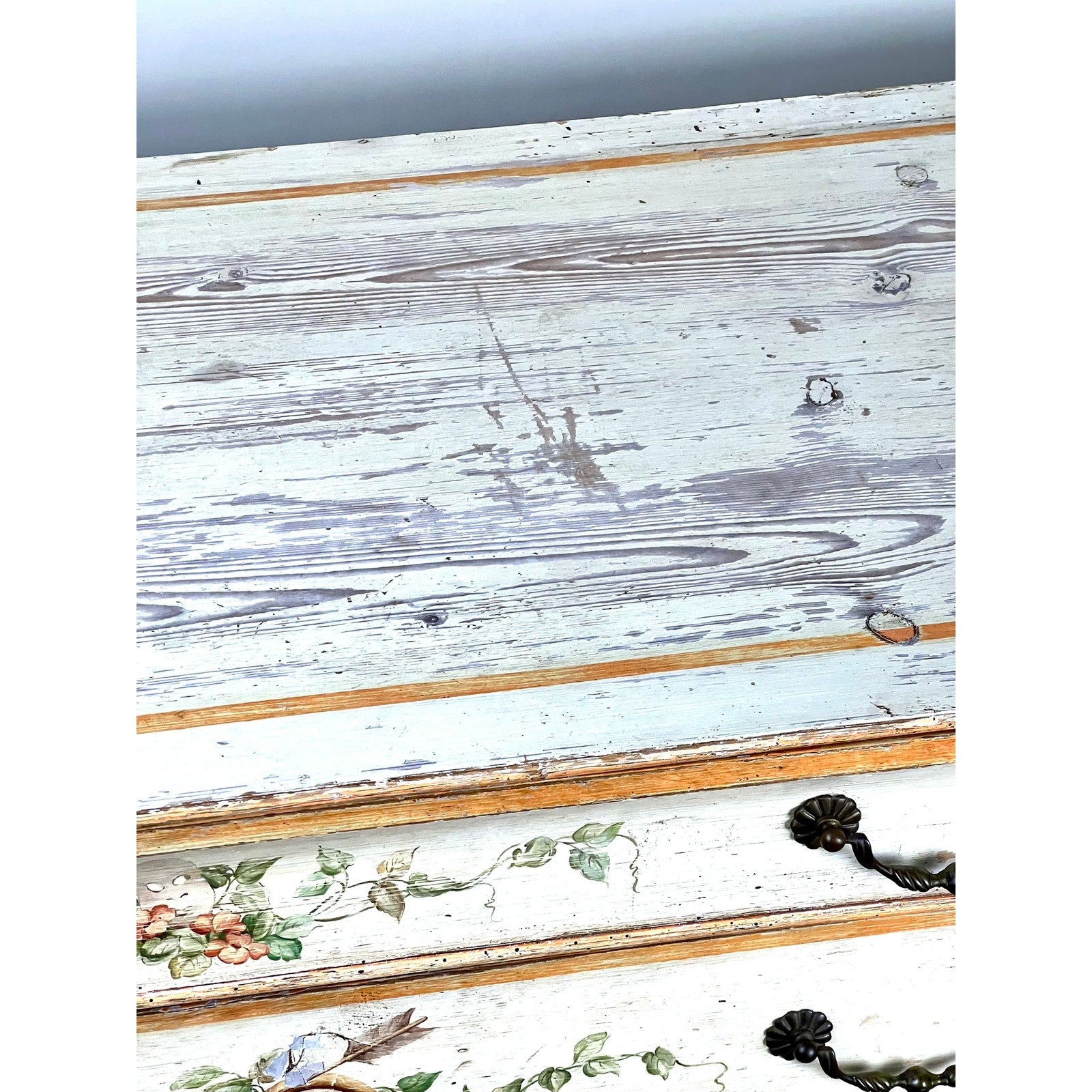 A close-up of this Antique Italian Paint Decorated Four Drawer Commode (c. Early 19th Century) shows weathered wood, peeling white paint, floral and bird motifs, ornate black handles, and aged details typical of provincial Italian furniture.
