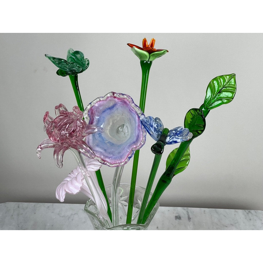 The Vintage Bouquet Murano Art Glass Long Stem Flowers and Butterflies features colorful, hand-blown glass flowers and butterflies in a clear vase on white marble, creating a striking vintage centerpiece against a light gray background.