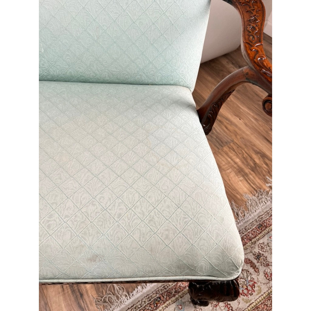 A close-up of an Antique George II Mahogany Gainsborough Open Arm Chair, c. Mid 19th Century, featuring light blue diamond-patterned upholstery, ornate wooden armrest, and part of a patterned rug on a wooden floor.