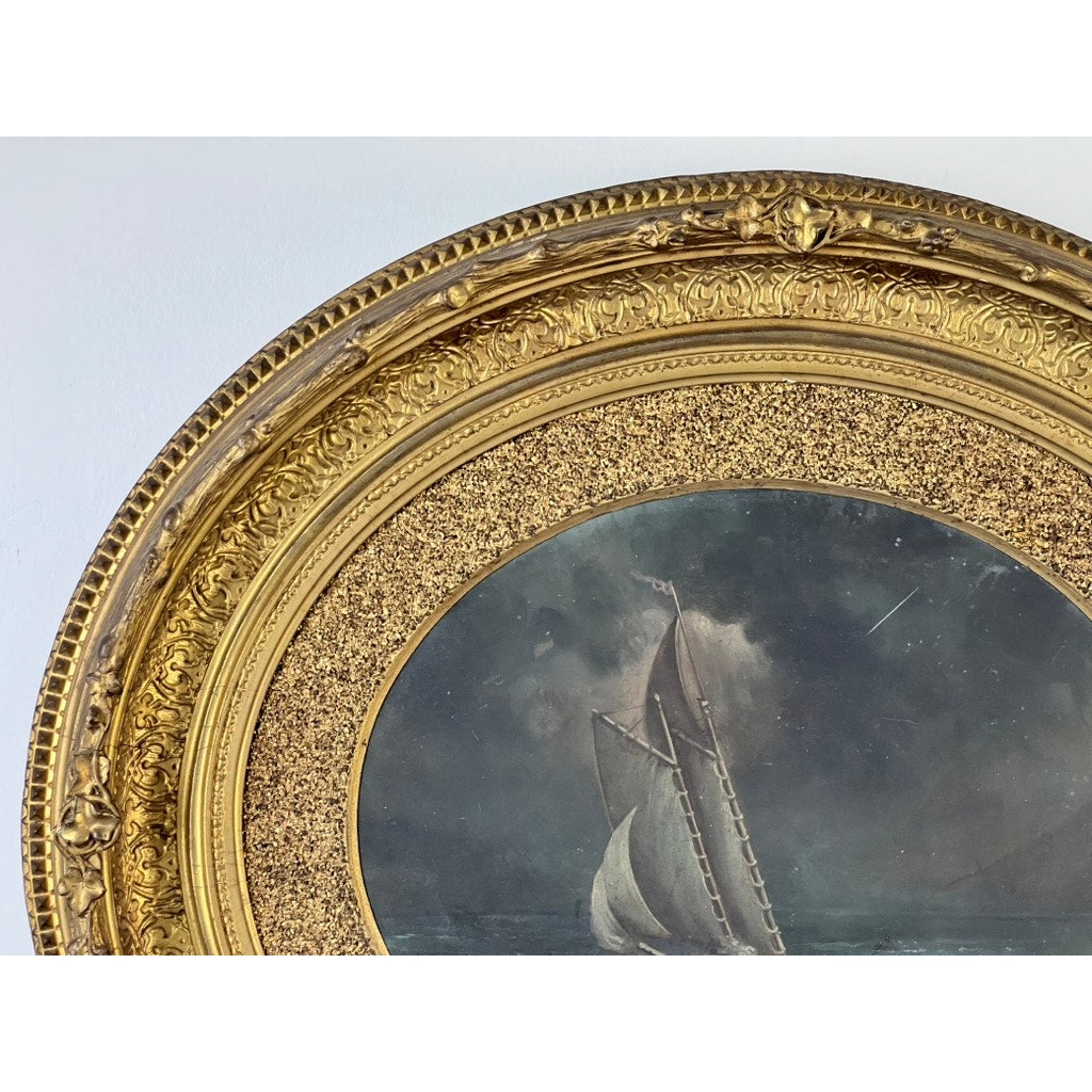 A close-up of the upper left section of an ornate gold frame and painting shows the Antique Oval “Storm Tossed Ship” Oil on Board Painting, c. Late 19th Century, depicting a sailboat braving stormy seas under a cloudy sky.