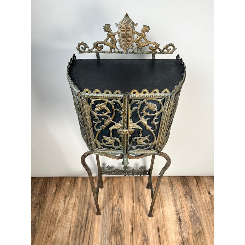 Antique Gothic Revival cast iron and brass phone stand, attributed to Oscar Bach or Bertram Segar c. 1920, Greenwich Village. Features ornate scrollwork, two lions, a crest, and stands on four slender legs against a plain white wall. Brand unknown.