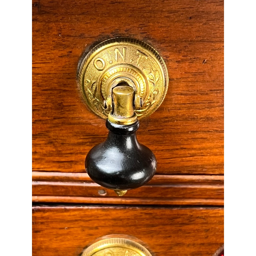 Close-up of a black ornate handle labeled Clark’s ONT, attached to the polished pine drawer of an Antique Victorian Two Drawer Clark’s ONT Spool Cabinet c. Late 19th Century by Clark's ONT.