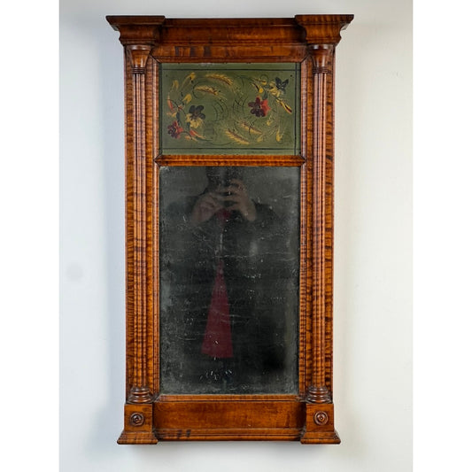 Fine Antique Federal Period Tiger Maple Two Panel Mirror c. 1820 by Pearl City Antiques, showcasing a rectangular tiger maple frame with fluted columns and a floral motif atop the upper panel. The mirror’s gently worn reflective surface speaks to its early 19th-century American heritage, and the faint image of a person taking a photograph can be seen in the glass.