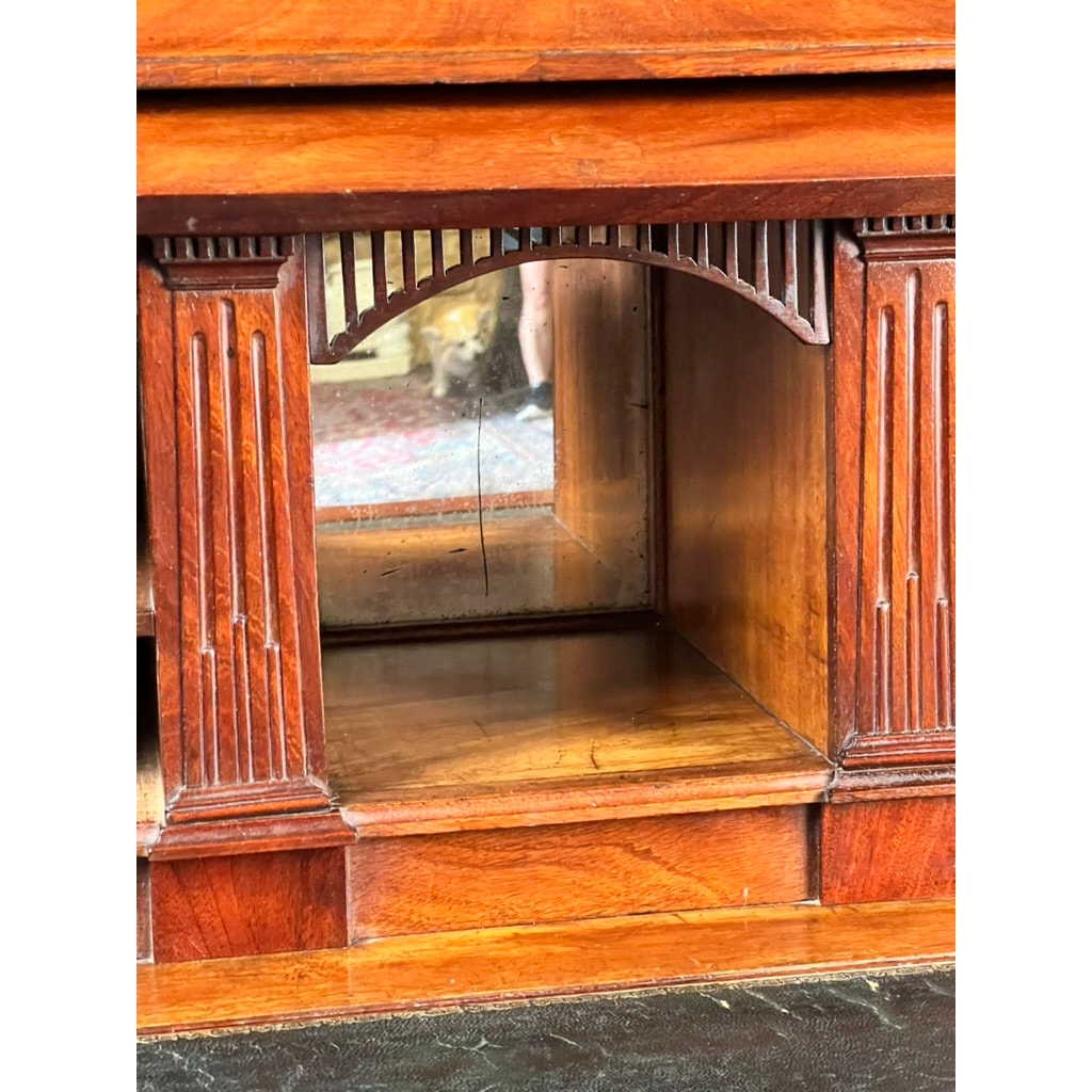 Close-up of an Antique Directoire Style French Cylinder Desk with Slate Top (late 19th century), featuring a wooden compartment with fluted columns, detailed trim, and a mirrored back panel reflecting a room's patterned rug.