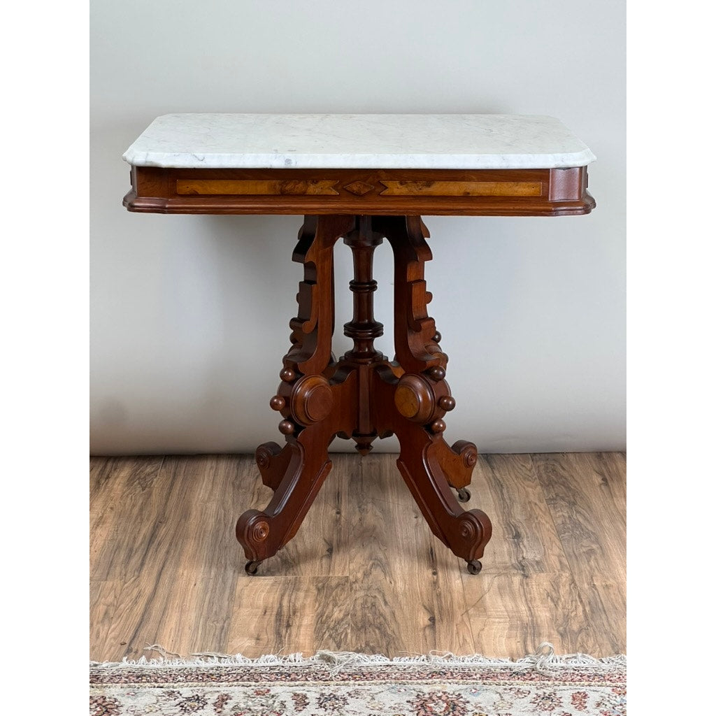 Antique Eastlake Victorian Walnut Marble Top Stand, late 19th century, with ornate legs and a white marble top, shown on a wooden floor with part of a patterned rug visible below. Brand: None/Unknown.