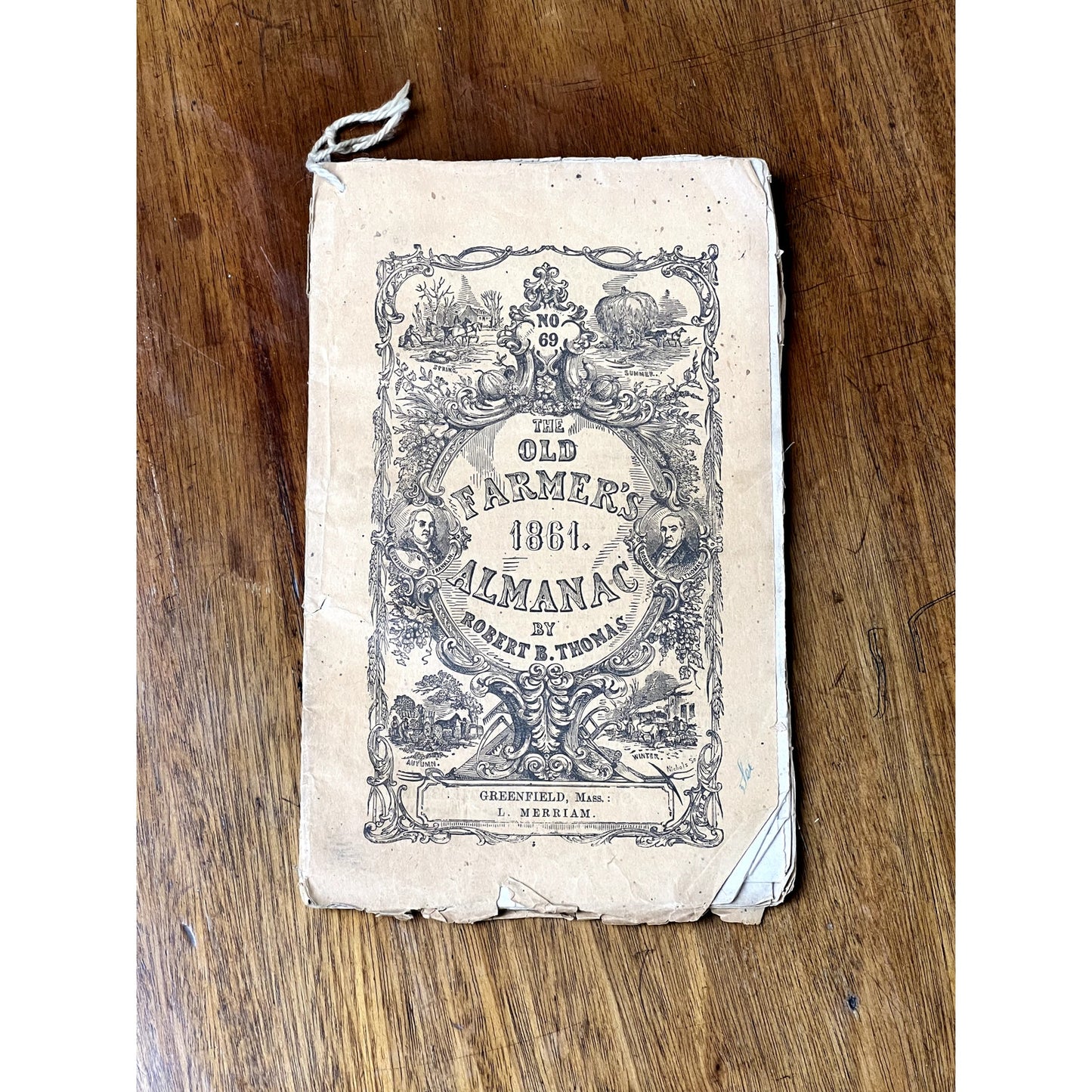 An antique set of four Old Farmer’s Almanacs (1858, 1861, 1864 & 1865) by Robert B. Thomas lies on a wooden surface—a striking example of early American print and rare 19th-century Americana.