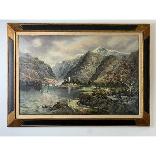 Framed oil on canvas painting titled “Mountain Lake” by Alfred Worthington (British, 1835-1927), signed lower right, depicts a winding road beside a calm lake bordered by tall mountains and trees, with a small building near the water under a cloudy sky—a beautifully evocative Victorian landscape in the classic 19th-century style. Offered by Pearl City Antiques.