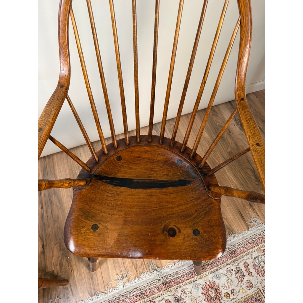 Pair of signed L.E. Partridge Connecticut bench-made continuous-arm Windsor chairs, c. 1960s, featuring a curved spindle back, visible wood grain, and a distinctive dark streak across the seat. These handcrafted pieces embody the timeless elegance and classic lines of early American furniture craftsmanship. Shown on a hardwood floor beside a patterned rug and against a plain light-colored wall. Brand: None/Unknown.